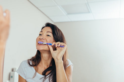 Woman brushing teeth in the bathroom