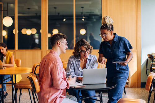 Coworkers collaborating on a project with a laptop in a modern office