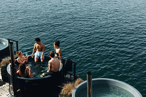 An outdoor spa brings people together by the water for a relaxing escape with drinks