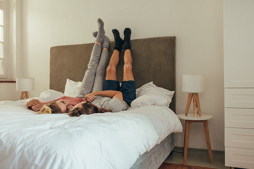 Romantic couple lying on bed together with raised legs