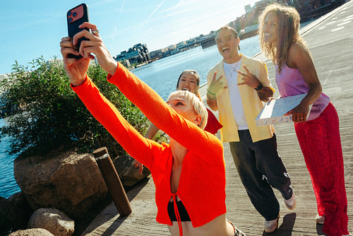 Urban friends line up for a selfie with a smartphone by the pier