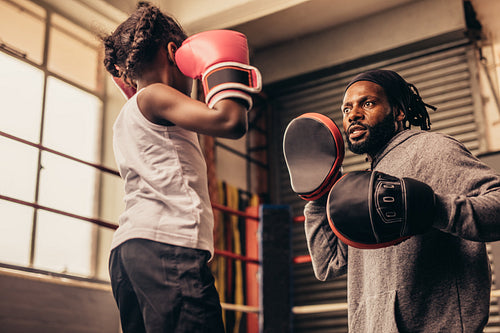 Boxing kid practicing punches wearing boxing gloves.