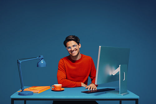 Happy male office colleague posing in colorful workspace