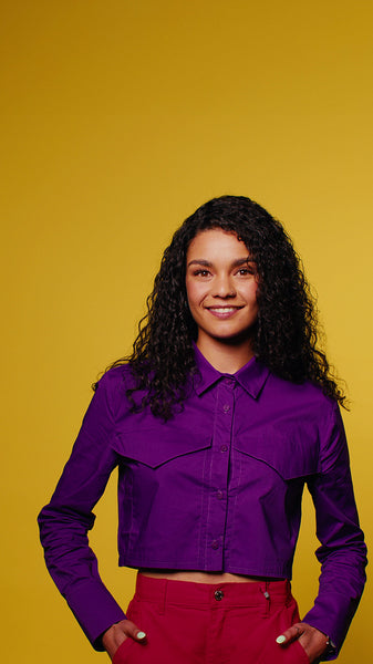 Smiling young woman with curly hair on yellow background