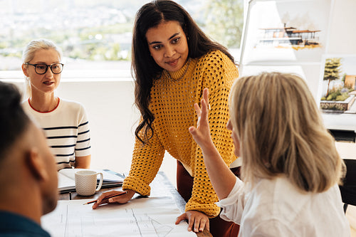Young and senior architects discussing a project in a collaborative office environment.