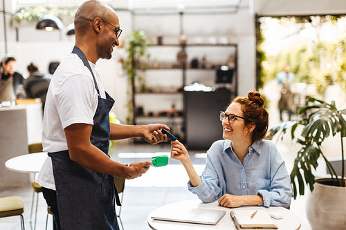 Woman handing her credit card to make a payment in a cafe