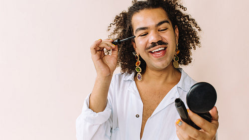 Confident young gay man doing his eyebrows