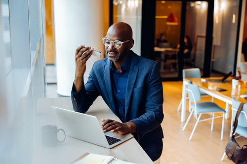 Business professional using a laptop and phone in a corporate office
