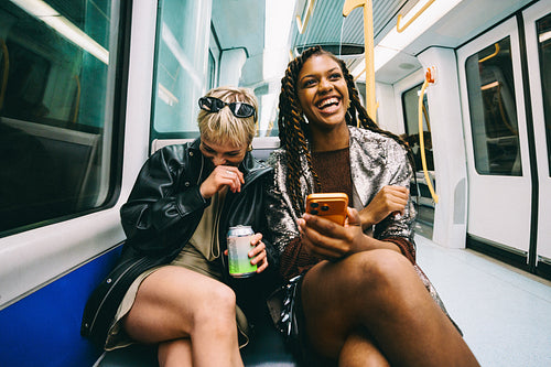 Smartphone fun on the train: friends laughing together on the metro