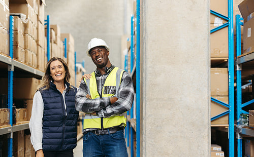 Cheerful warehouse workers smiling while standing together