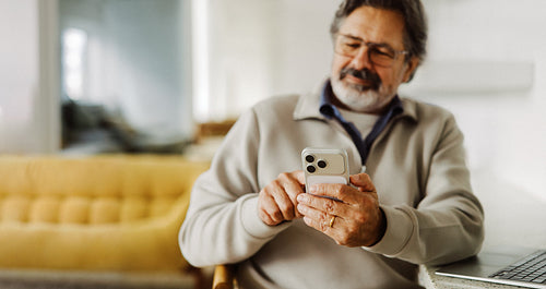 Senior browses the internet on a smartphone at home