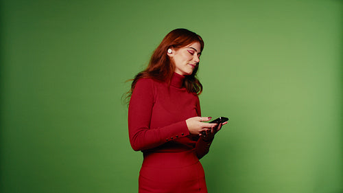 Woman in red clothes enjoys music on green screen