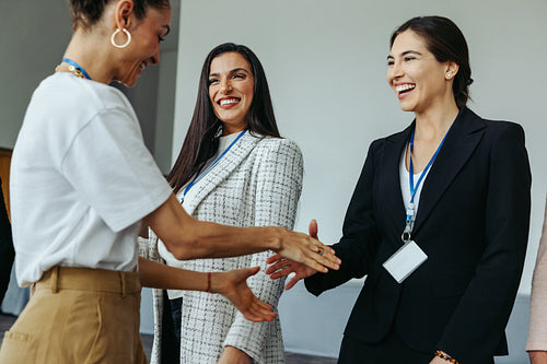 Female colleagues congratulating each other with joyful smiles in a professional setting