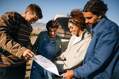 Planning the route: Friends gather around a map by their camper van