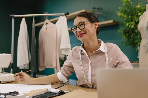 Smiling female dressmaker working at her desk