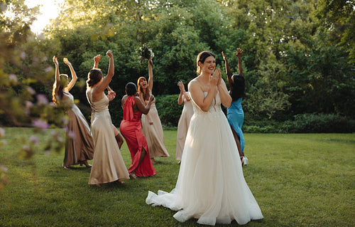 Bride and bridesmaids celebrating outdoors during a cheerful bouquet toss