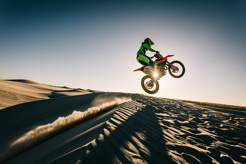 Motocross racer jumping over the dune