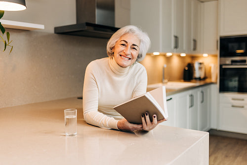 Senior woman smiling happily while reading a book