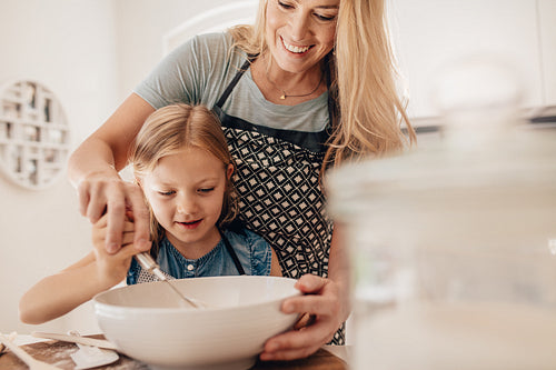 Mother and daughter kneading dough in kitchen