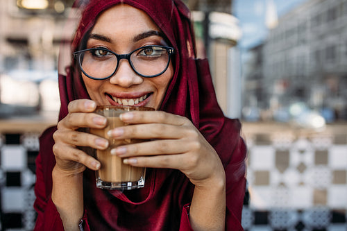 Smiling woman hijab having coffee at cafe