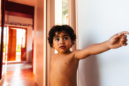 Young child pointing enthusiastically in a brightly lit home interior