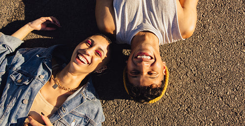 Top view of two friends lying down outdoors