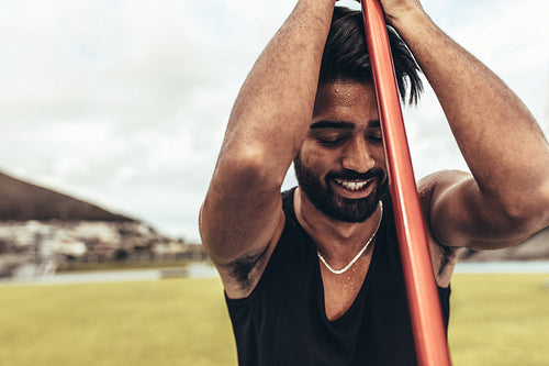 Tired athlete relaxing standing in the ground holding a javelin