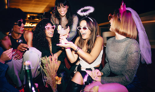 Group of women enjoying a bachelorette party with laughter and props
