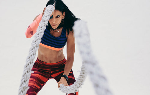 Close up of a fitness woman working out using battle ropes