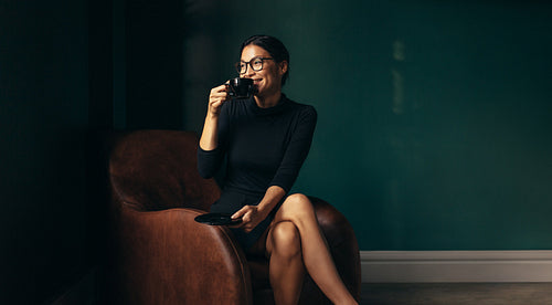 Happy businesswoman drinking coffee and looking away
