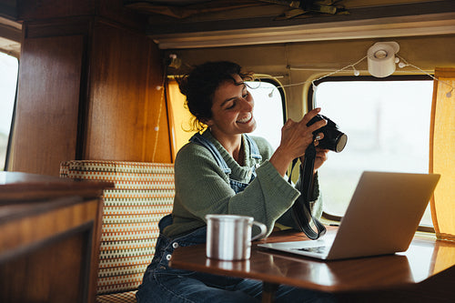 Reviewing the shot: Woman adjusts her camera during a break in the camper van