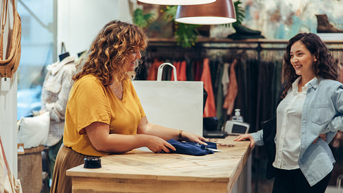 Shop clerk assisting customer at clothing store checkout