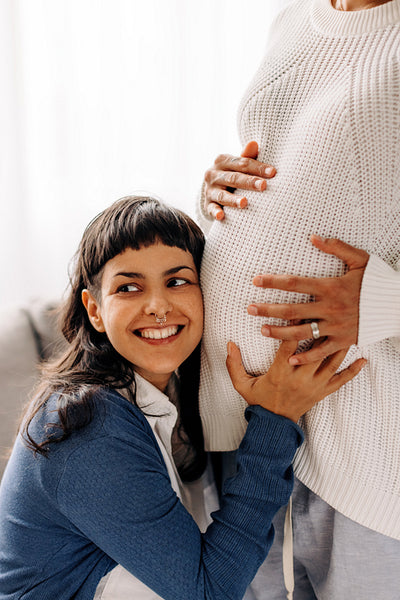 Young lesbian woman listening to her unborn baby kicking