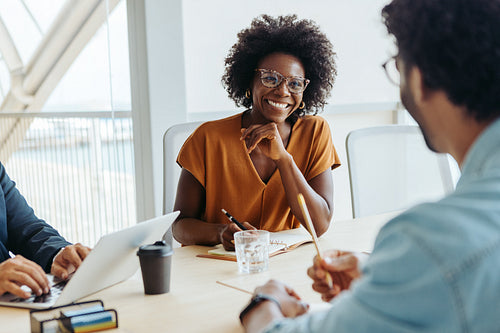 Black business woman leading a group of colleagues in a modern office boardroom