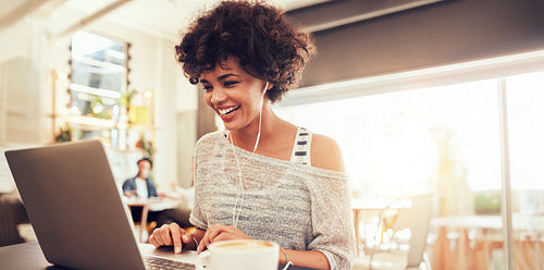 Young woman working as digital nomad on laptop in a coffee shop