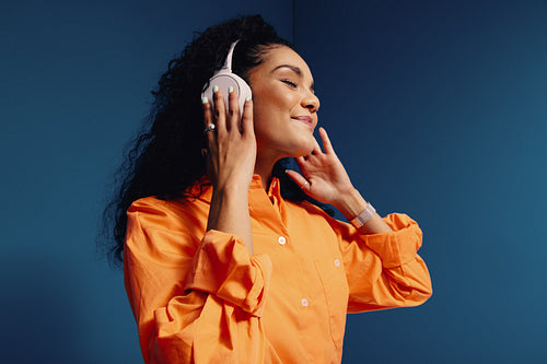 Woman enjoying music with headphones in vibrant orange and blue colorblock studio space