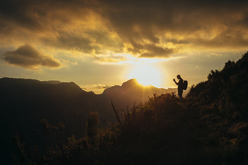 Hiker taking pictures of mountain valley at sunset