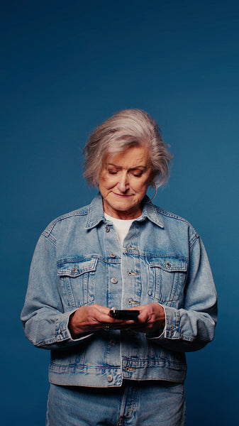 Happy senior woman using phone on blue background
