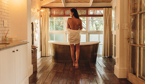 Rearview of a woman taking off her shirt for a bath