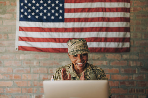 Happy female soldier video calling her family on a laptop
