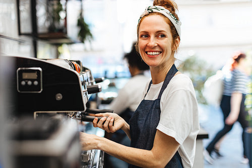 Happy waitress brewing fresh coffee for a customer in a coffee shop