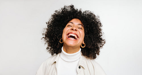 Woman with curly hair laughing cheerfully in a studio