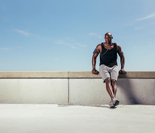 Young man relaxing on embankment after his run