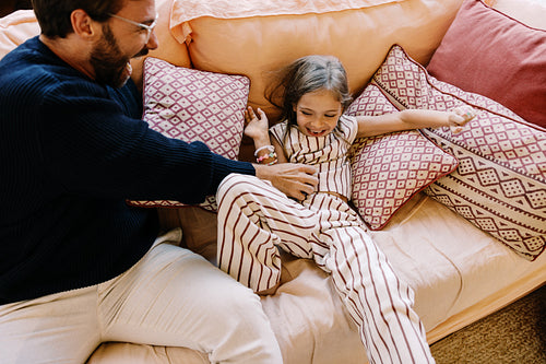 Family moment as dad plays with daughter on couch