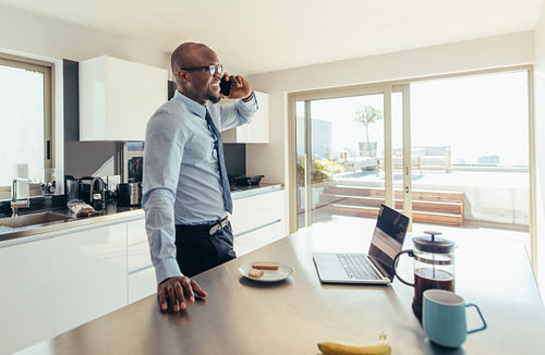 Man talking over phone while having breakfast