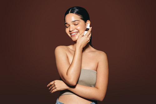 Achieving healthy looking skin using skincare products: Happy young woman holding a beauty serum