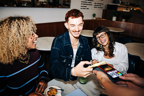 Friends making a contactless payment at cafe