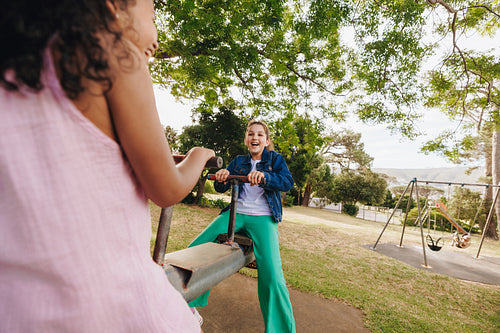 Children playing together on a seesaw in a sunny outdoor park