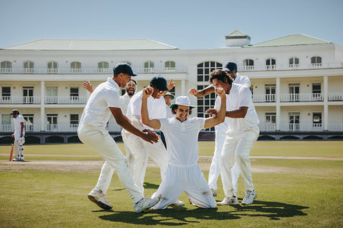 Cricket team celebrating a triumph on the field on a sunny day
