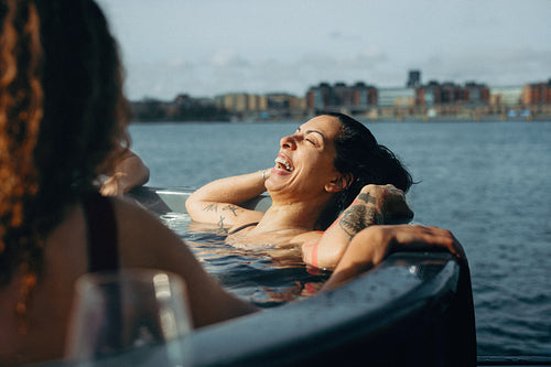 Woman relaxing in a hot tub with friends by the waterfront